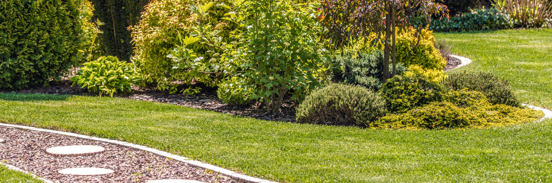 flower bed and stone walk way surrounded by green grass